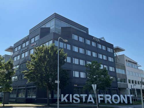 Receptionsdisk och skymt av trappor inuti en stor och luftig byggnad.